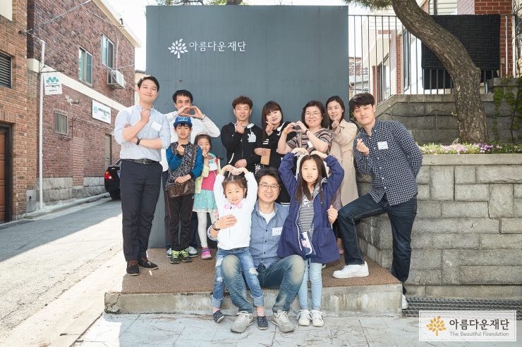 기부자들이 재단 앞에서 자유롭게 하트를 만들며 찍은 단체사진