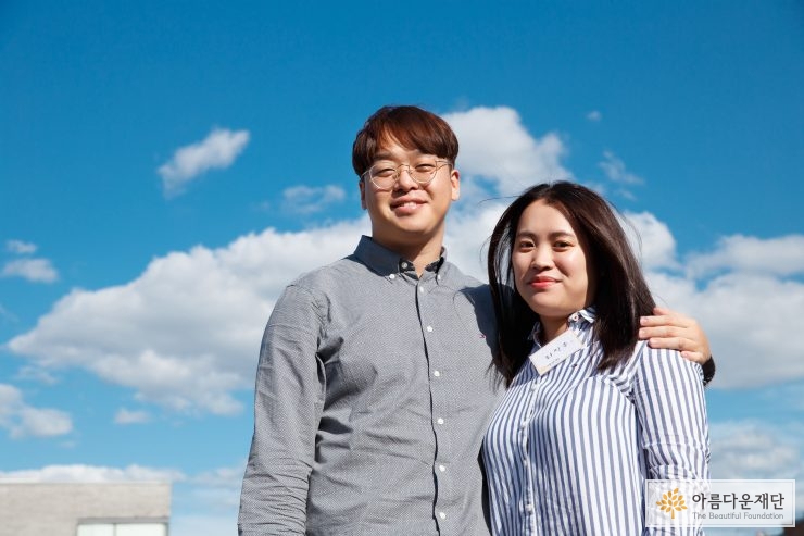 옥상 하늘을 배경으로 찍은 부부 기부자의 다정한 모습