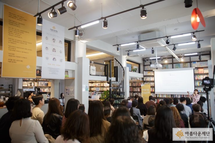 책방 행사로 강연자가 앞에서 앉아서 말을 하고 있고, 자리에 앉은 참석자들의 뒷모습이 보인다
