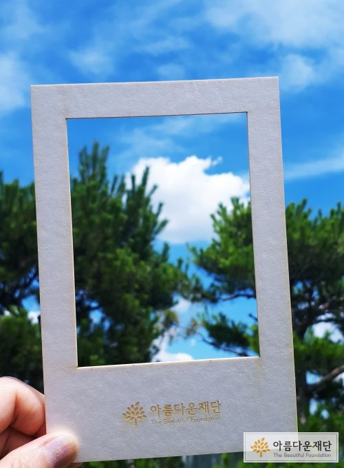 흰색 포토프레임 안에 하늘과 구름 나무를 넣어 찍은 사진