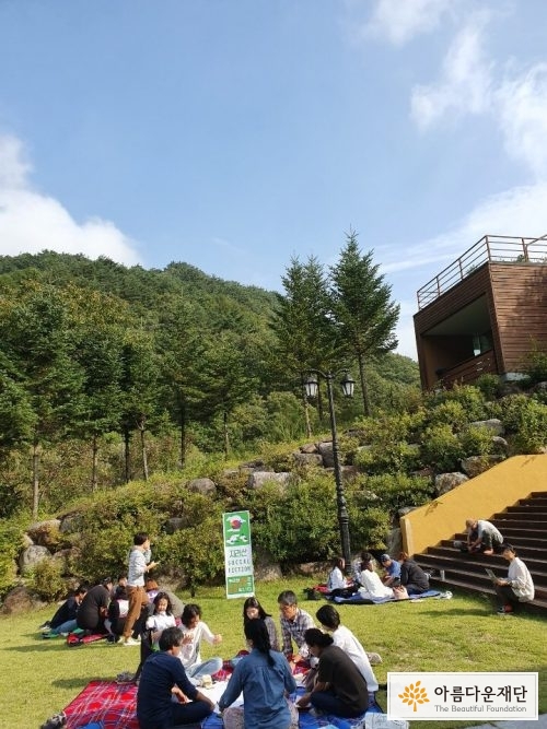 잔디밭에 그룹으로 둘러 앉아 이야기를 나누는 사람들. 