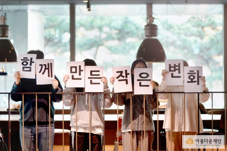함께 만든 작은 변화라는 여섯글자를 들고 있는 사람들