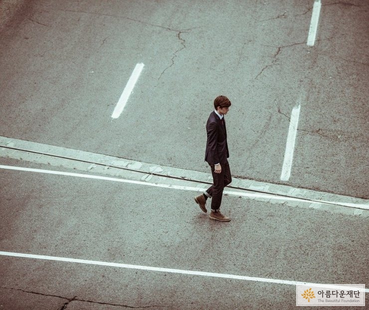 도로 위를 걷는 정장 입은 남자 이미지