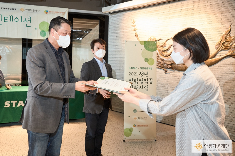 지원증서 및 기념품 전달 – 좌측부터 스타벅스커피코리아 대표 송호섭, 아름다운재단 사무총장 권찬, 지원사업 참가자