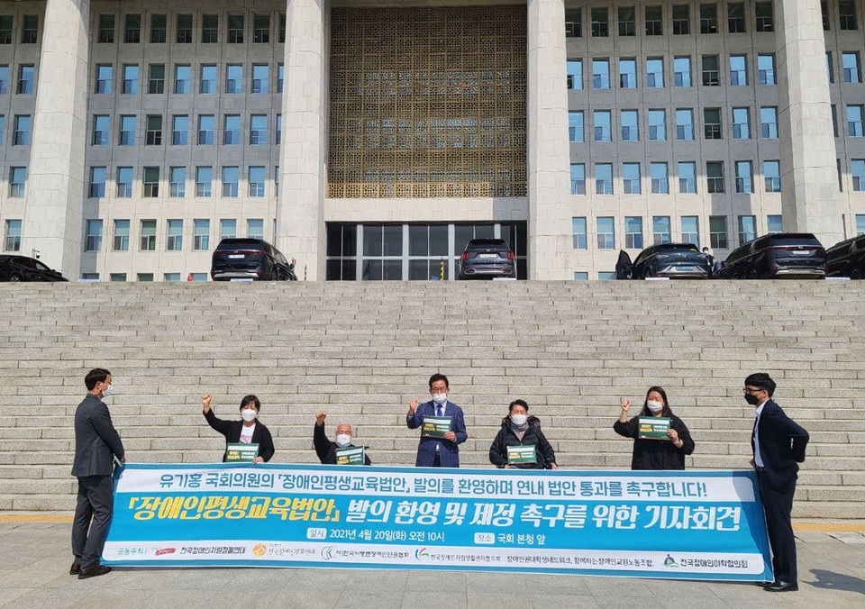 피켓을 든 사람들이 국회 앞에서 장애인평생교육법안 발의 환영 및 제정을 촉구하는 기자회견을 진행하고 있다.