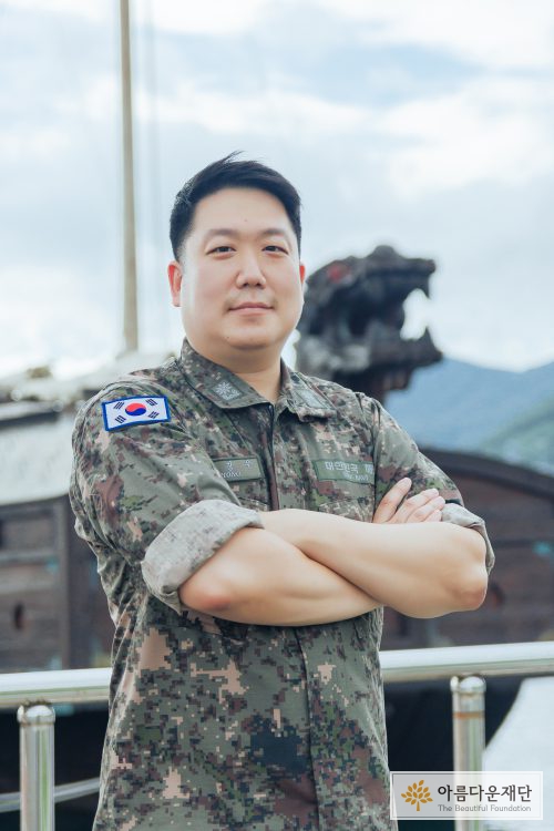 홍창우 기부자가 해군사관학교 교육용 거북선 앞에서 팔짱을 낀 늠름한 모습으로 서 있다.