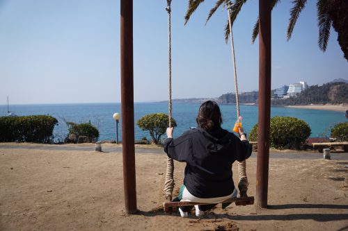 바닷가 앞에서 그네를 타고 있다.