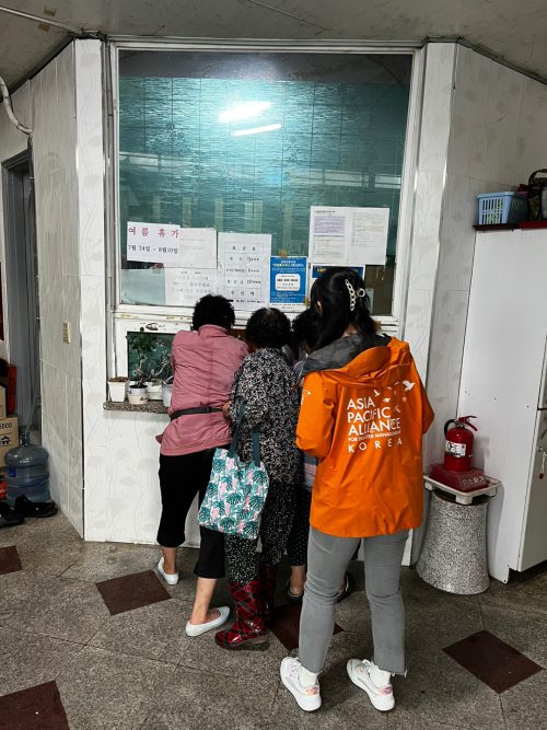 어르신들과 에이팟코리아 활동가가 목욕탕에 들어가기 위해 매표소 앞에 서있다.