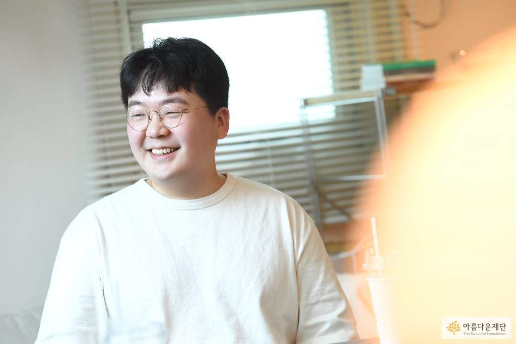 최민욱 활동가가 오른쪽을 향해 밝은 웃음을 보이고 있다. 