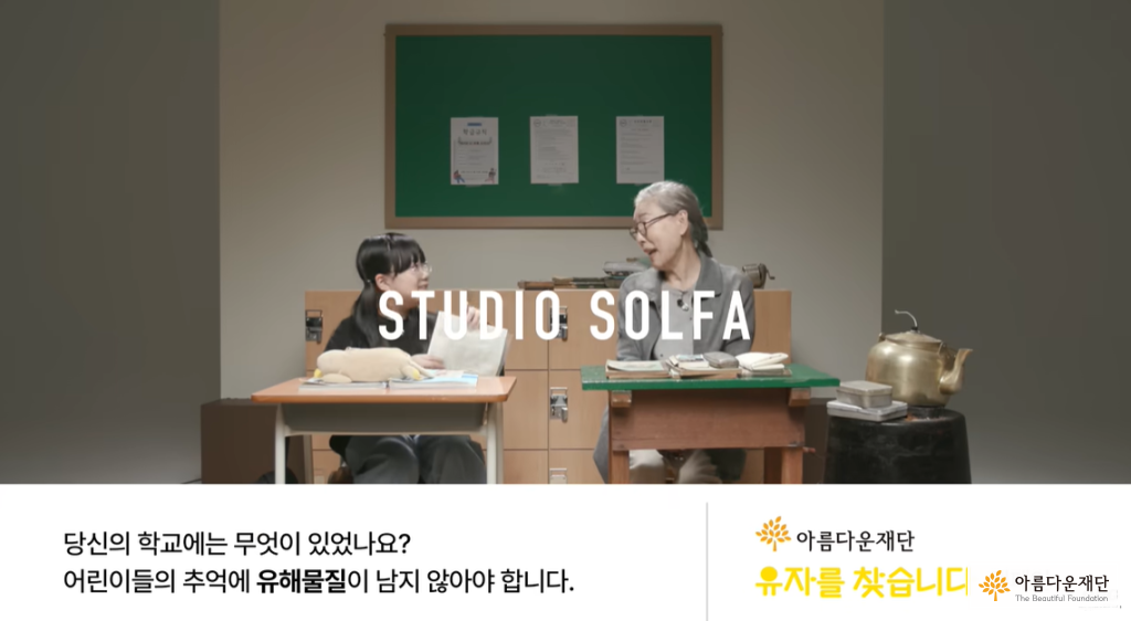 초등학생 정도의 여자아이와 할머니가 학교 책상에 앉아 서로 마주보고 있다