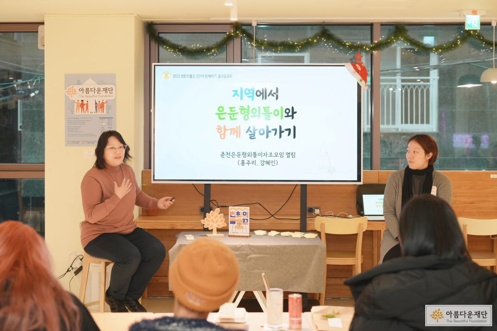 지역에서 은둔형 외톨이와 함께 살아가기라는 발표 자료 앞에서 두 명이 앉앙서 설명하고 있고, 자리에 앉아있는 사람들의 뒷모습이 보인다. 