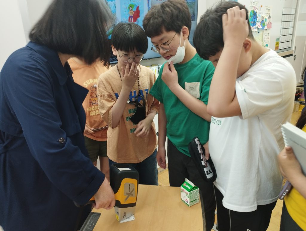 XRF기기를 통해 유해물질 수치를 확인하는 아이들