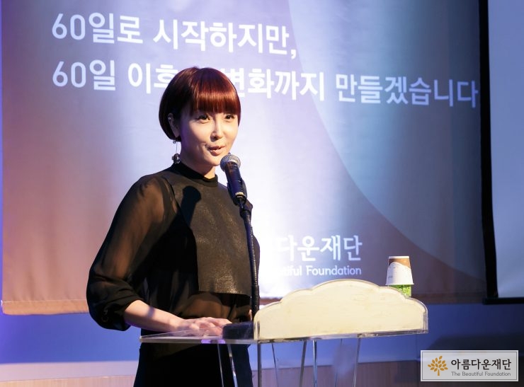 검정색 옷을 입은 최은경 아나운서가 단상 앞에서 마이크로 말을 하고 있다.