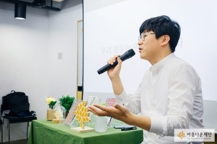 김민섭 작가가 앉아서 마이크를 들고 말을 하고 있다
