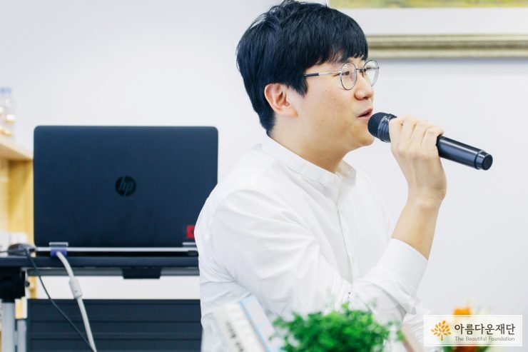 마이크를 들고 앉아서 강연을 하는 김민섭작가의 오른쪽 모습
