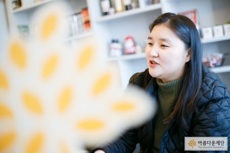 검은색 옷을 입은 긴 생머리의 여자가 이야기 하고 있는 오른쪽 측면의 모습