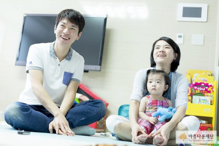 아이를 안고 앉아있는 엄마와 아빠