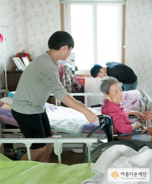 한 남학생이 할머니의 휠체어를 밀어드리고 있다