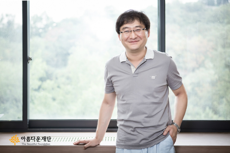 중년남성이 카메라를 향해 환하게 웃고 있다