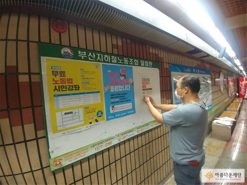 지하철 게시판에 기초수급 권리찾기 전화상담 포스터를 붙이는 사진