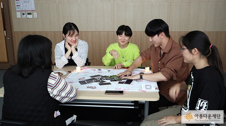 타로카드를 놓은 테이블을 둘러싸고 앉아 대화하는 청소년들