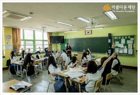 학교 아이들이 손을 들어 발표를 하려 하고 있다
